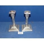 A pair of weighted George V Silver Candlesticks having column form on square bases with acanthus