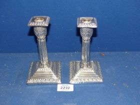 A pair of weighted George V Silver Candlesticks having column form on square bases with acanthus