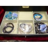 A black jewellery box containing various bracelets including, metal, leather, charm bracelets,