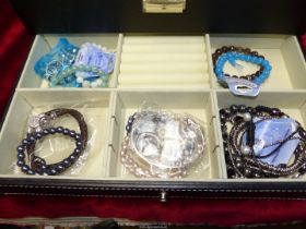 A black jewellery box containing various bracelets including, metal, leather, charm bracelets,