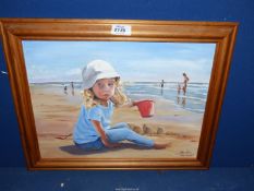 A wooden framed oil on board of a beach scene titled "Red Bucket" depicting a young girl building a
