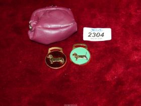 A red leather Purse containing two enamel dachshund tags.