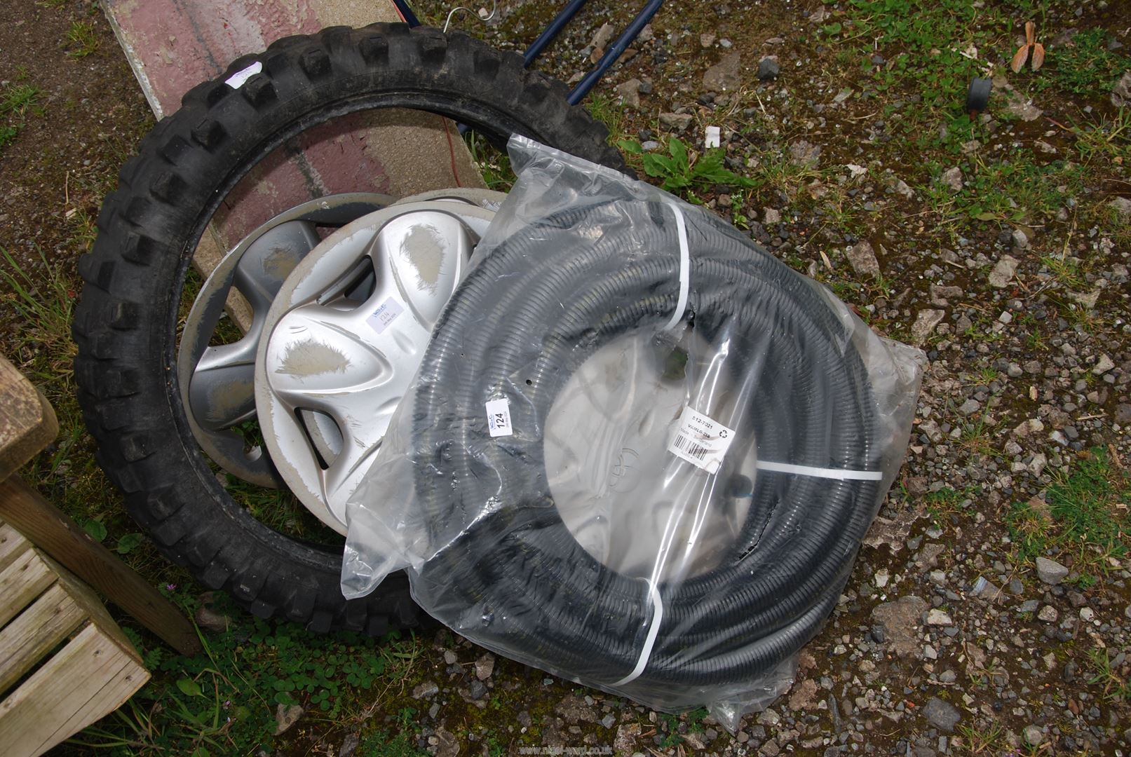 A motor cycle tyre, wheel trims and plastic hose.