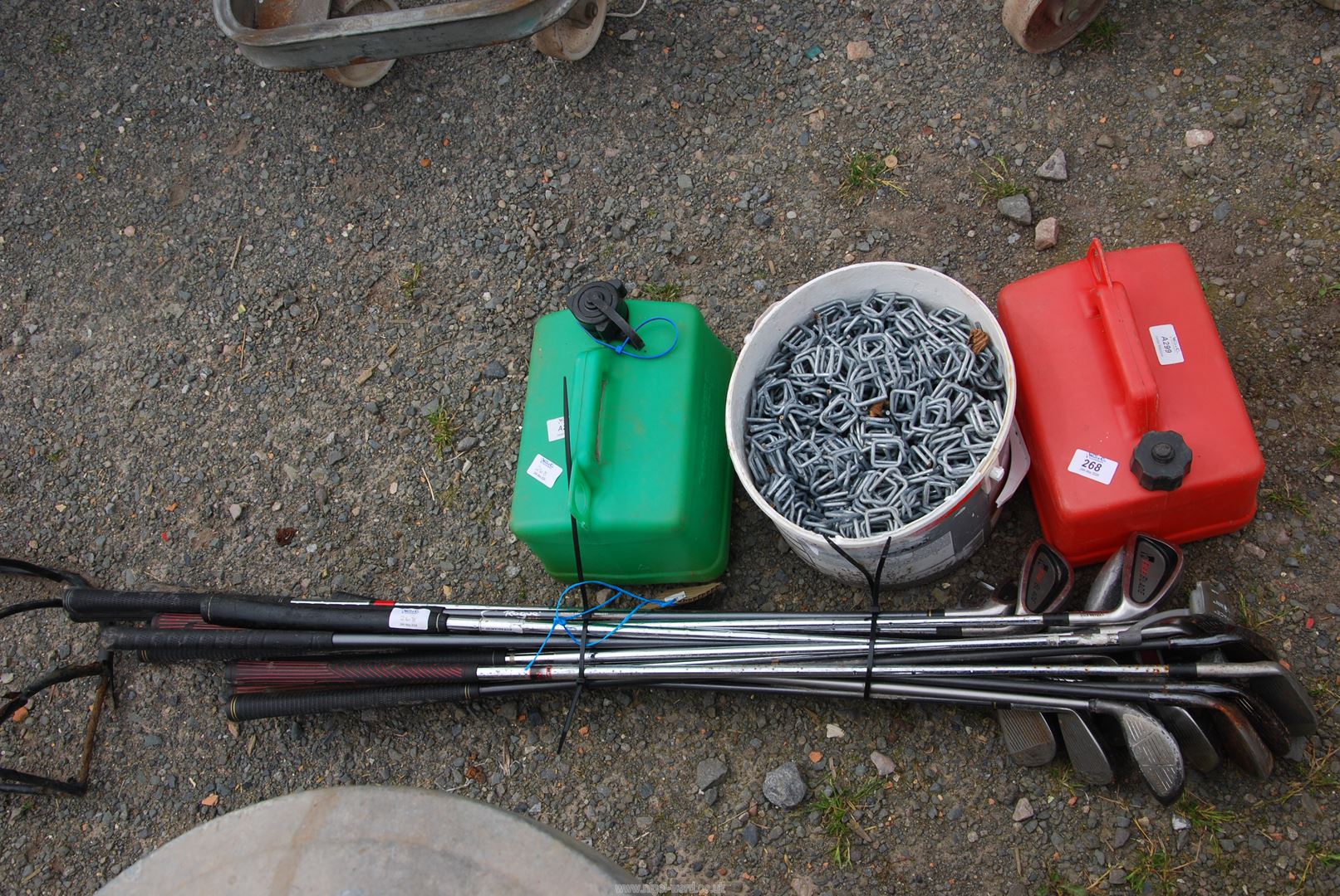 Two plastic fuel cans, a quantity of golf clubs and a tub of fencing clips.