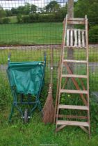 A wooden stepladder, a besom and a folding garden wheel barrow.