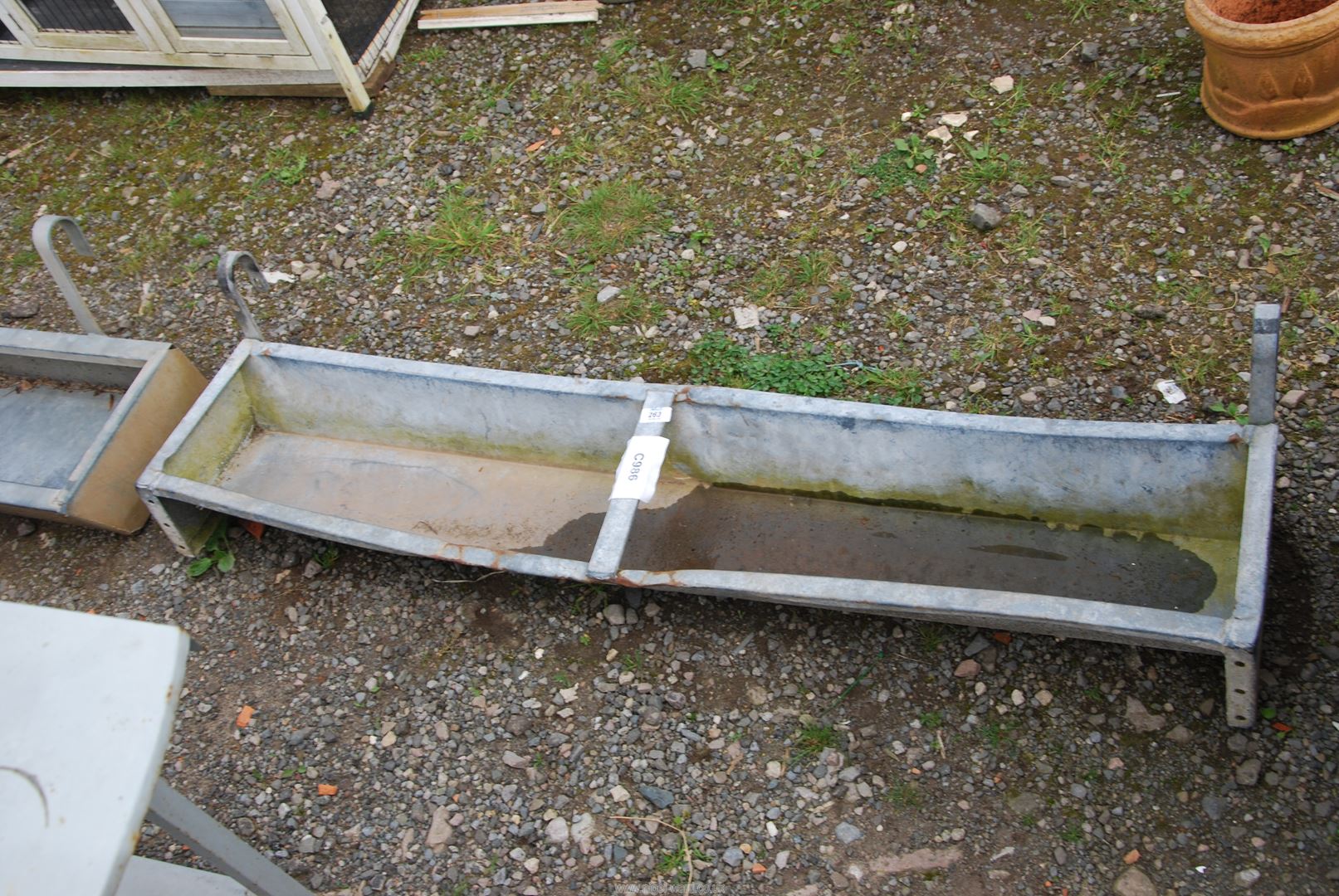 A galvanized gate hanging animal feeder, 53" long x 1' x 5" deep.