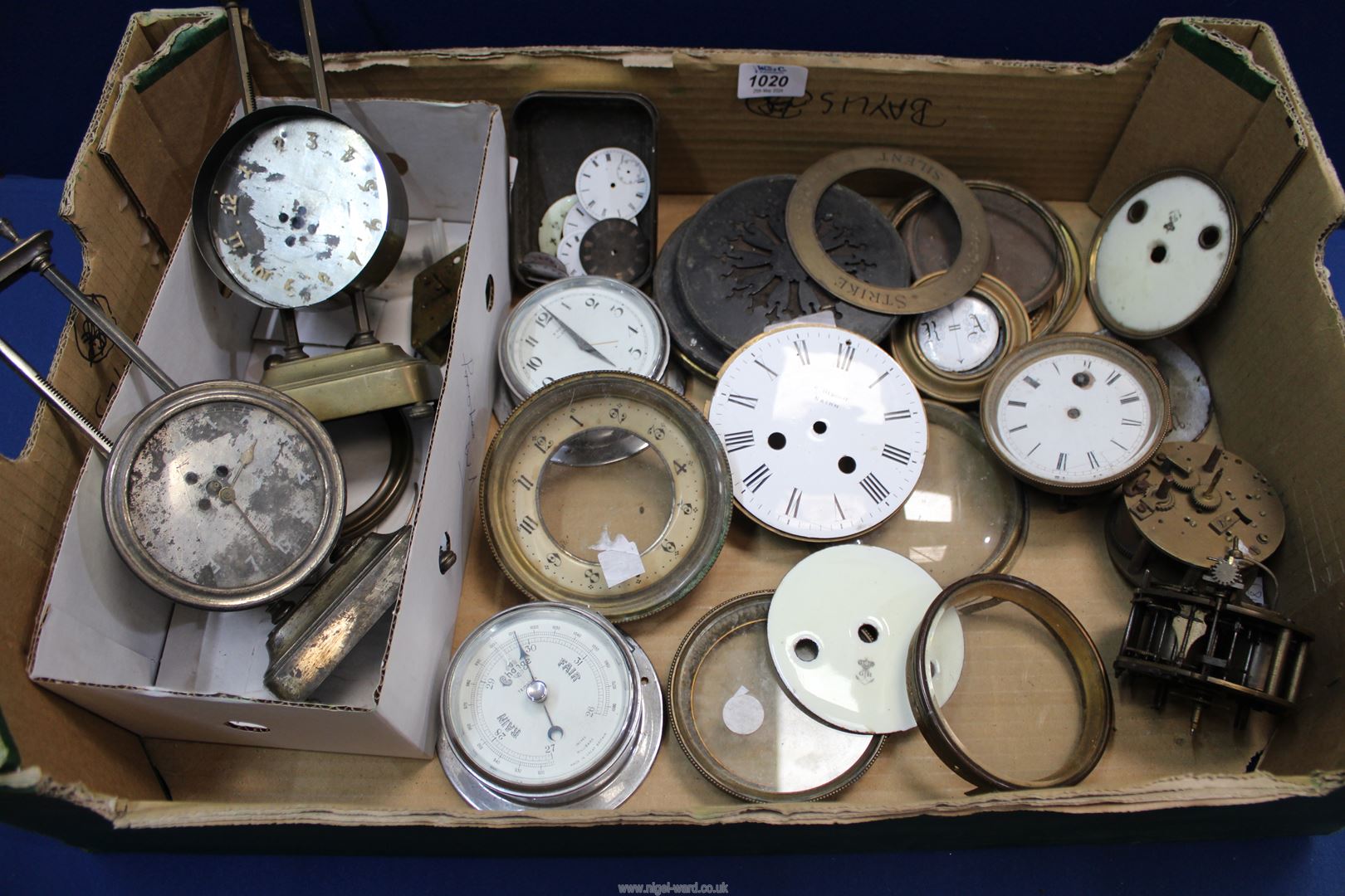 A collection of French clock parts including three movements, enamelled dials,