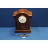 A Mahogany dome topped mantle Clock, with two train movement with Arabic numerals on a white face,