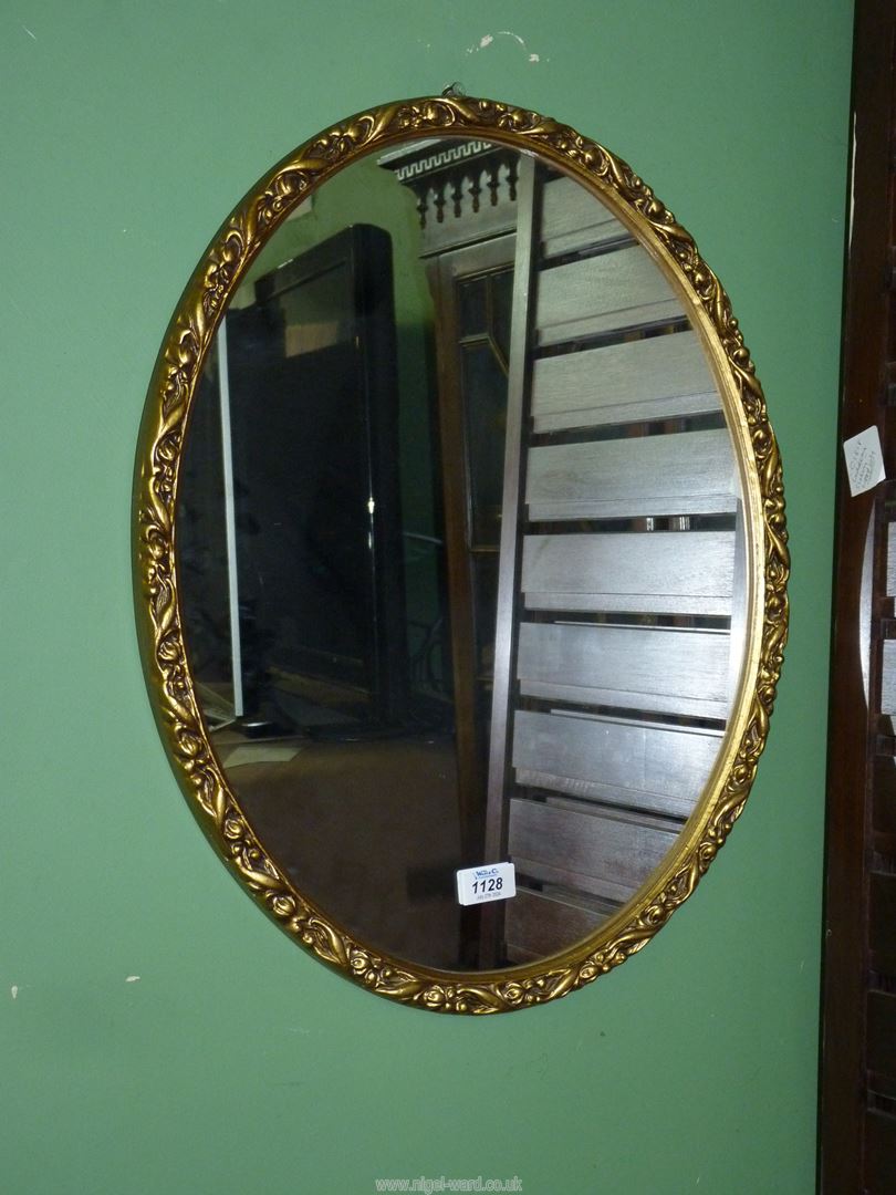 An oval wall mirror with a gold coloured floral moulded frame 22 1/4" x 18 1/4".