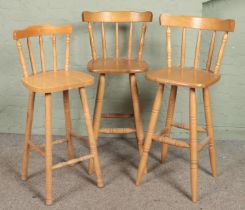 Three beech stools with spindle backs and turned supports.