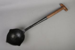A vintage smelting ladle with cast iron bowl and wooden handle. Stamped WD on wooden section and