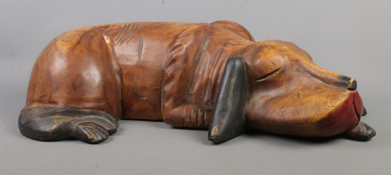 A large carved wooden figure of a sleeping dog. Length: 60cm.