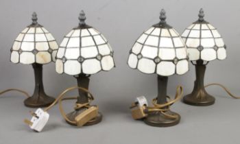 Four small Tiffany style desk lights, with translucent shades. One example has smashed panels, two