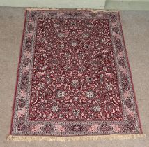 A red ground wool rug, with all over floral decoration and frilled edge. Length: 203cm, Width: