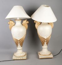 A pair of gilt decorated table lamps formed as twin handled urns with shades.