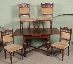 A carved oak drawer leaf table along with four late Victorian dining chairs.