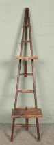 A slender set of wooden ladders of A-Frame form, possibly for fruit picking. With seven rungs and