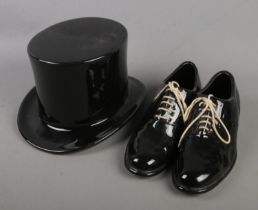 A ceramic top hat along with a pair of ceramic dress shoes decorated with white laces.