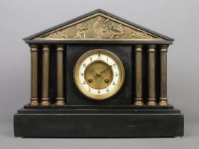 A black slate mantle clock, with Corinthian pillars and battle scene detailing. Features Arabic