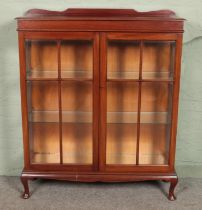 A mahogany display cabinet with two glazed doors with bevelled edge glass and glass interior shelves