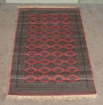 A pink ground Bokhara rug, with blue patterned border and frilled edge. Length: 212cm, Width: 139cm.