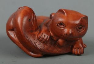 A hand carved hardwood netsuke of a cat with fish, signed to base.