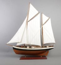 A vintage wooden pond yacht, raised on rectangular stand, with multiple sails and miniature rowing