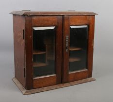 A vintage oak table top smokers cabinet with bevel edge glass doors.