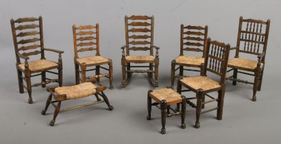 A collection of miniature/dolls house rush seat furniture. To include rocking chair, arm chairs