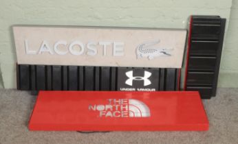 Three shop lighting signs; North Face, Lacoste and Under Armour, with one other. Missing power