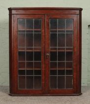 A large Georgian style oak wall mounted corner cupboard, with twin lead glazed doors. Height: 127cm,