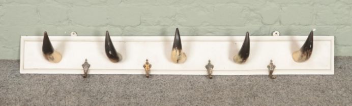 A wooden wall mounting coat rack with cattle horns. Length 110cm.