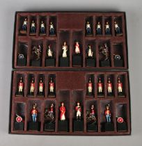 Two boxed sets of cast metal chess pieces formed as Napoleonic soldiers, raised on square bases.