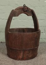 An antique wooden slatted well bucket with metal mounts and loop. Height: 50cm.