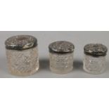 Three silver topped cut glass graduated jars.