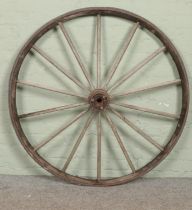 A large wooden cartwheel, with fourteen spoke design. 124cm diameter. Some spokes loose, signs of