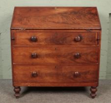 A Victorian three drawer mahogany bureau raised on turned supports. Height: 117cm, Width: 106cm,