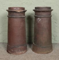 Two cylindrical chimney pots. 76cm tall. Chip to the rim of one example.