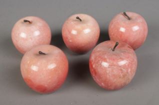 A collection of five pink marble apples.