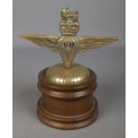 A brass parachute regiment badge, formed as a car mascot, mounted on turned wooden plinth. 20cm
