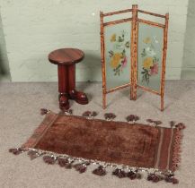 A small vintage bamboo and glass screen with a wool rug and novelty plant stand.