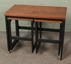 A mid century fold over coffee table with two nesting tables underneath produced by Mckintosh of