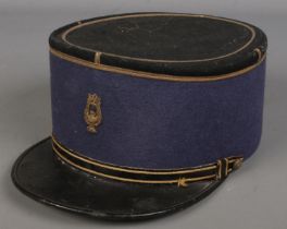 A military kepi baring stitched lyre insignia.