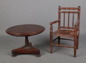 An early 20th century miniature mahogany tilt top table with column support and shaped base on bun