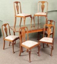 A carved walnut extending dining table with six matching chairs with floral upholstery seats.