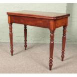 A Victorian mahogany fold over table. Marked and split to the top.