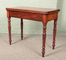 A Victorian mahogany fold over table. Marked and split to the top.