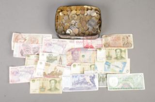 A tin of assorted world coins and bank notes, to include Suriname, Sri Lankan and Zambia examples.