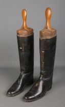 A pair of vintage black leather riding boots, with large wooden three-section boot trees, marked L