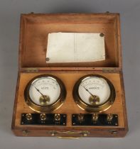 A pair of amperes and volts gauges in fitted wooden box